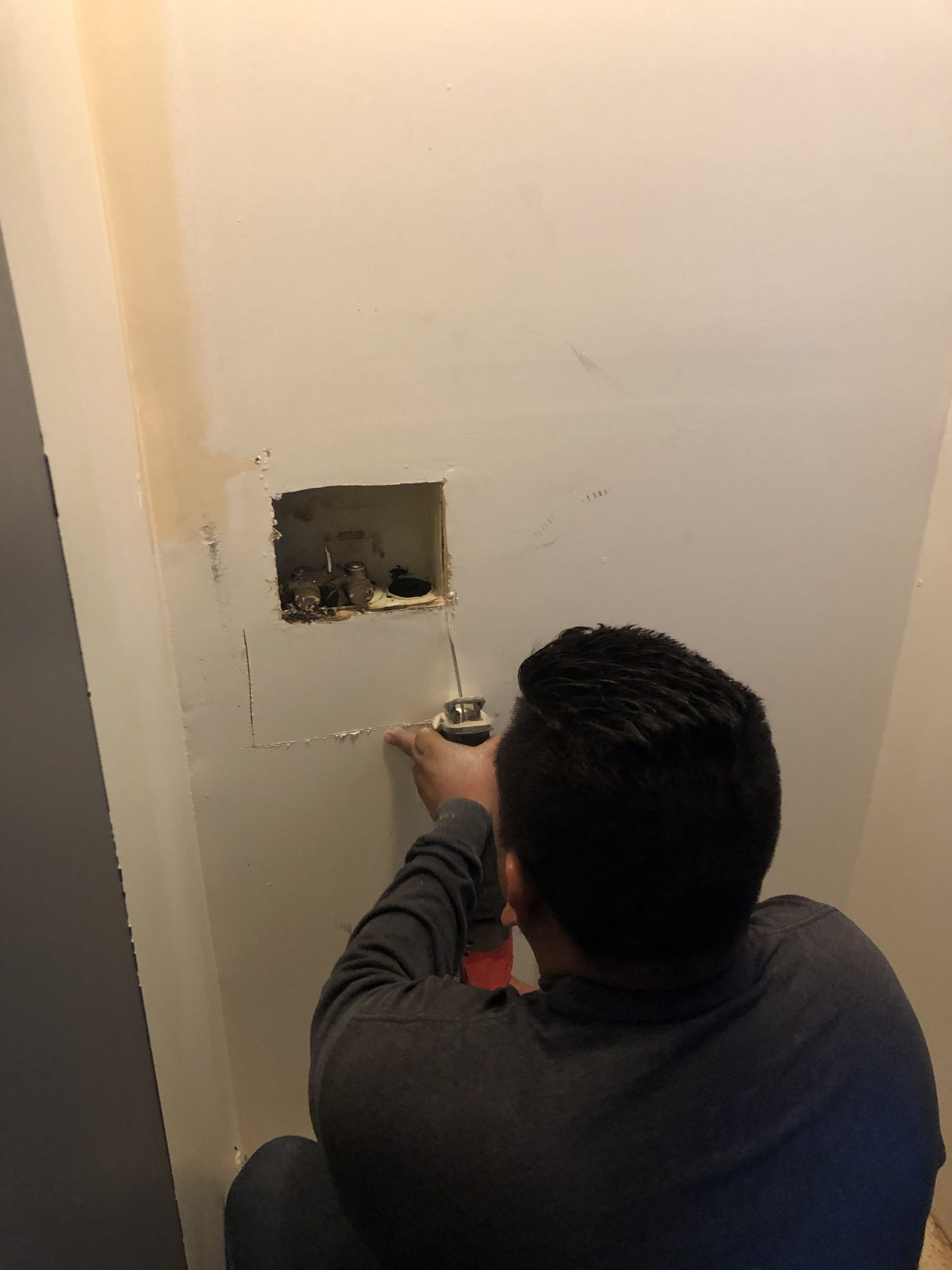 American Rat Control technician cutting a hole in a wall to find rats