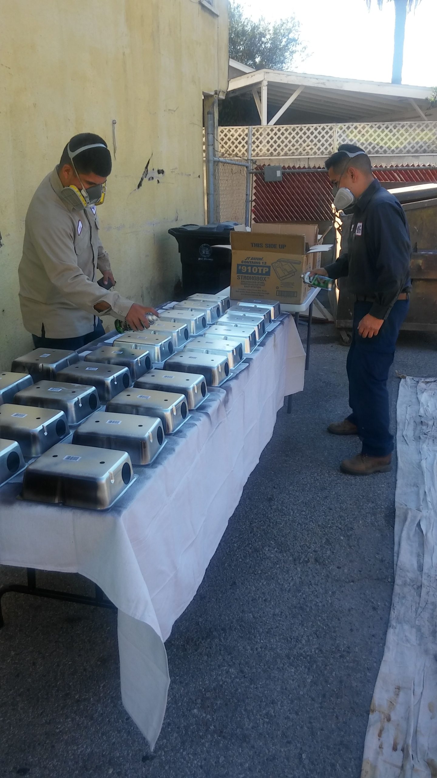 Rat exterminator technicians painting rodent bait stations